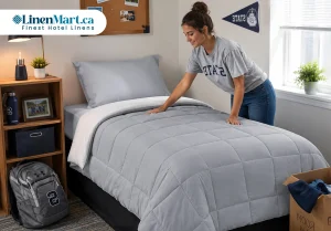 Student arranging a microfiber comforter on a dorm room bed in a modern student residence